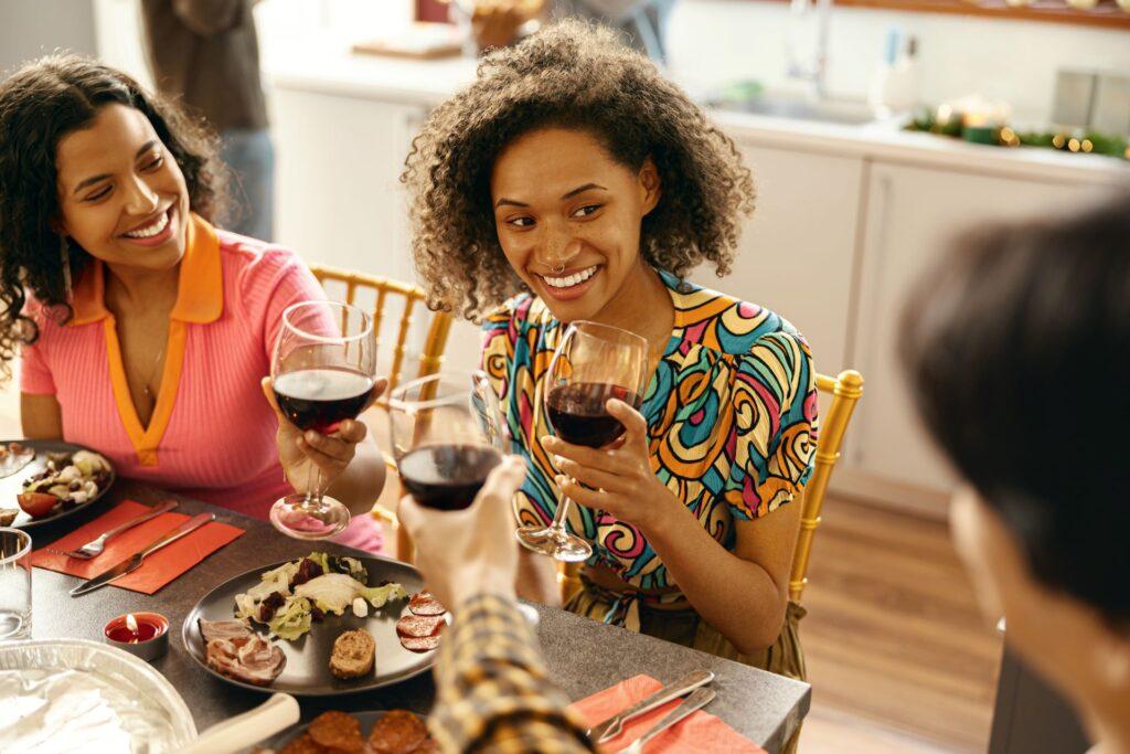 Glückliche Freunde unterhalten sich und trinken Wein während einer festlichen Party zu Hause