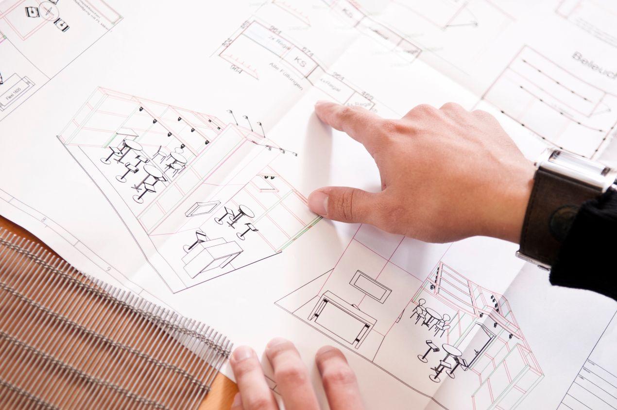 Hand zeigt auf architektonische Zeichnung mit Konzept für Wohnwaende und funktionale Raumaufteilung
