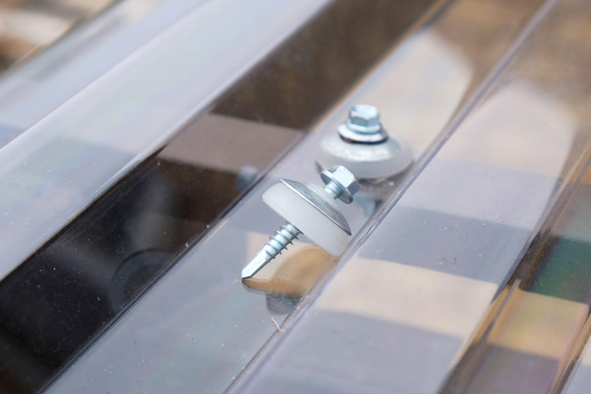 Nahaufnahme von Schrauben mit Dichtung auf transparenter Stegplatte – wichtig beim Stegplatten kaufen und montieren